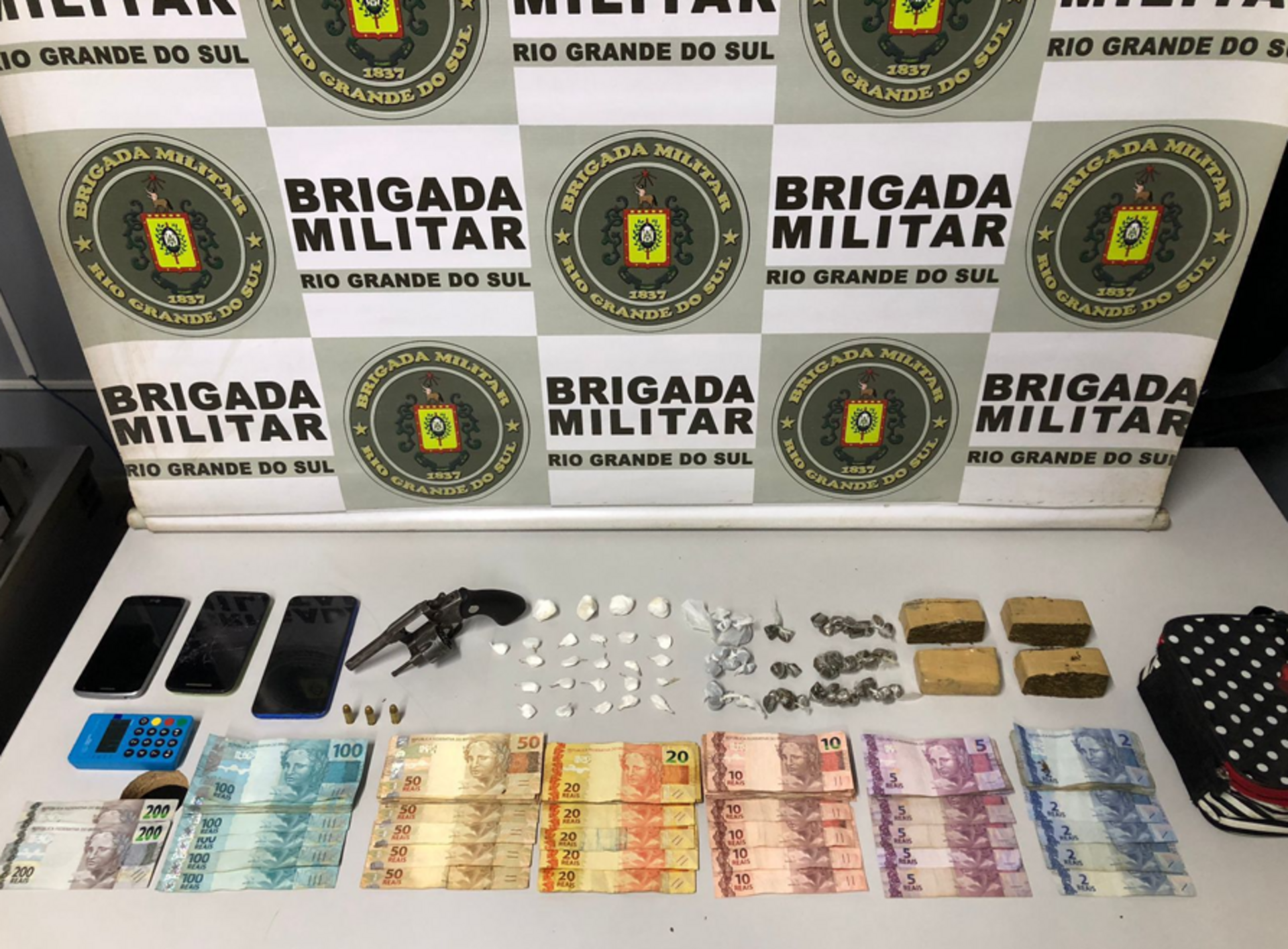 Acusados foram detidos pelo BP Choque, com arma, drogas, dinheiro e até uma máquina de cartão